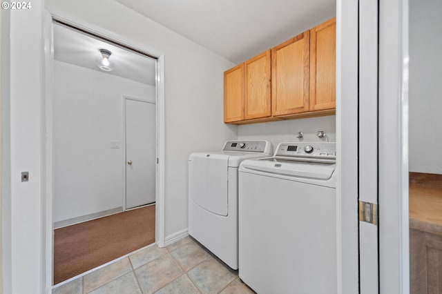 clothes washing area featuring washer and dryer, light tile patterned floors, and cabinets