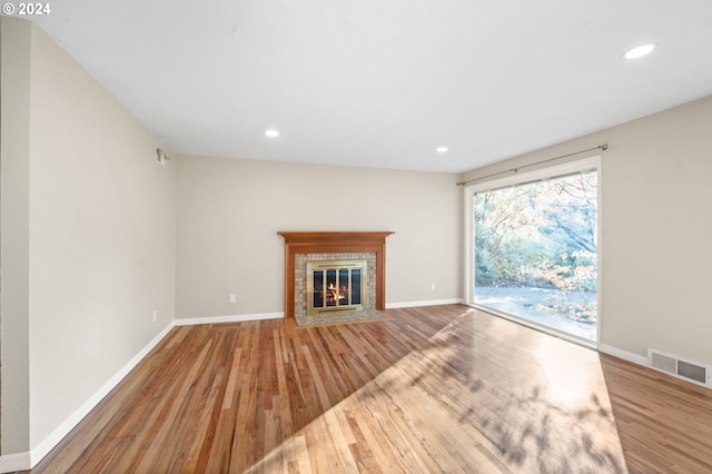 unfurnished living room featuring hardwood / wood-style flooring and a tiled fireplace