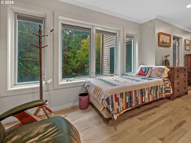 bedroom with baseboards, ornamental molding, multiple windows, and light wood finished floors