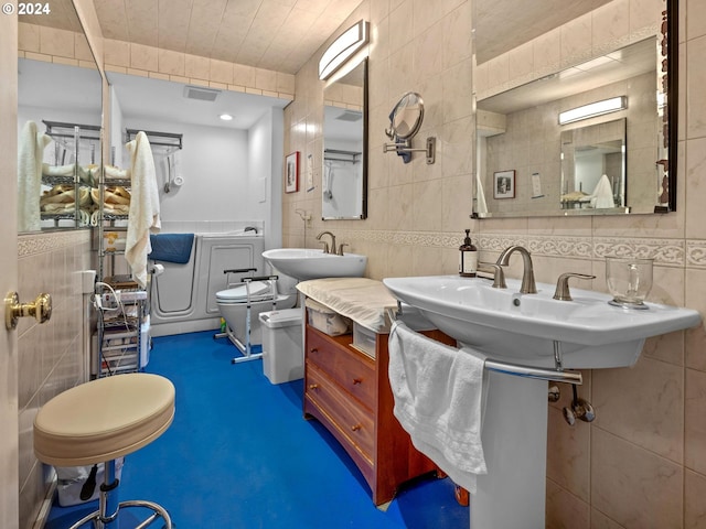 bathroom with toilet, sink, and tile walls