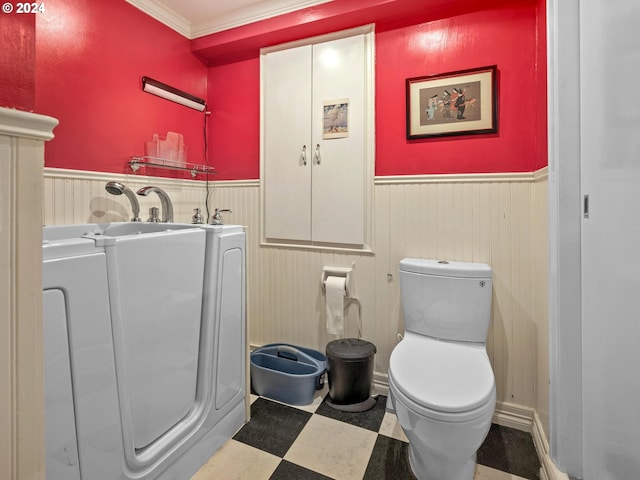bathroom featuring crown molding, tile patterned floors, a wainscoted wall, toilet, and washer / clothes dryer