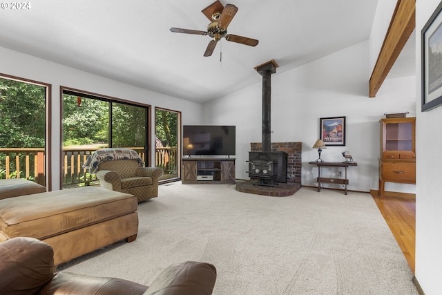 carpeted living room with vaulted ceiling, ceiling fan, and a wood stove