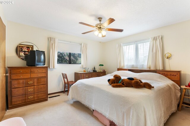 bedroom with multiple windows, light colored carpet, and ceiling fan