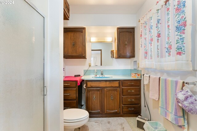 bathroom featuring a shower with shower door, vanity, and toilet