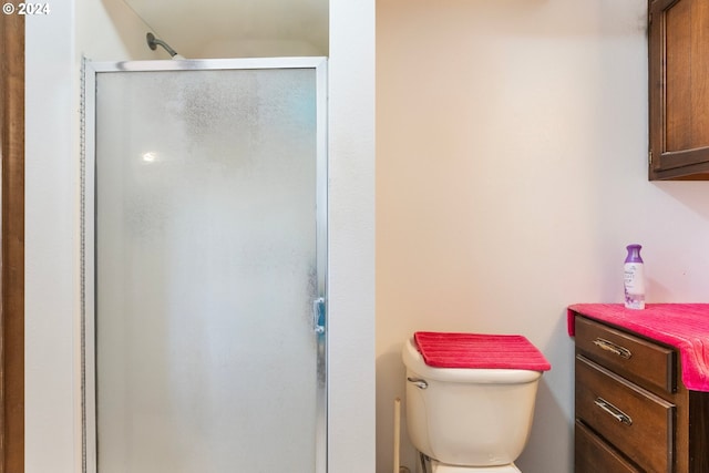 bathroom featuring vanity, a shower with shower door, and toilet