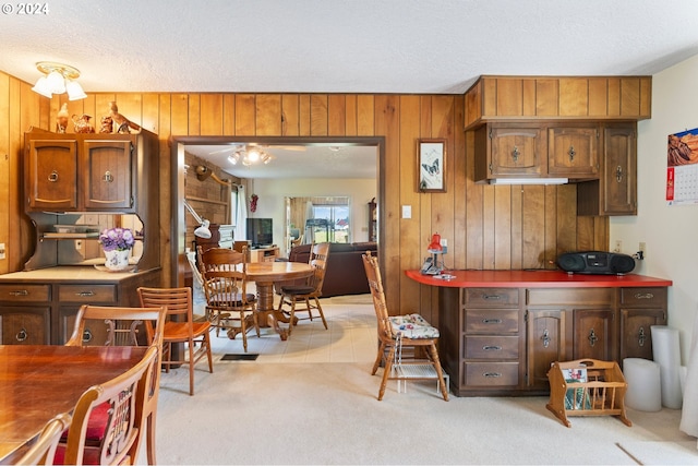 kitchen with a textured ceiling, wood walls, and light colored carpet