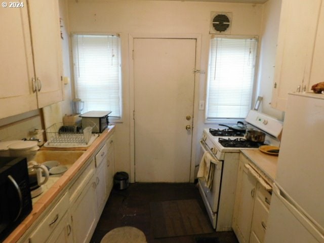 kitchen with white appliances, white cabinets, and tile countertops