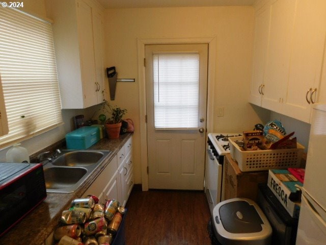 kitchen featuring white appliances, white cabinetry, dark hardwood / wood-style floors, and sink