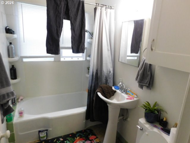 bathroom with shower / bath combination with curtain, toilet, and a wealth of natural light