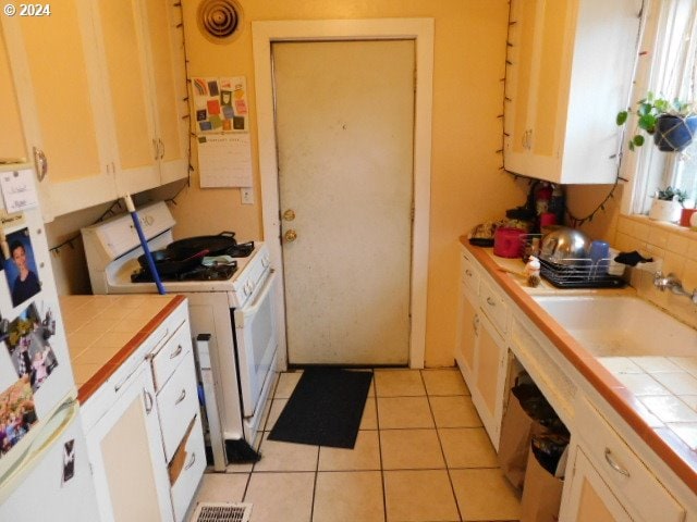 kitchen with sink, tile counters, white appliances, and light tile patterned flooring