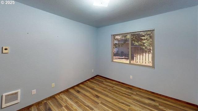 empty room featuring hardwood / wood-style flooring and a textured ceiling