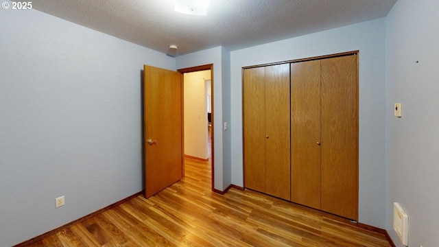 unfurnished bedroom featuring light hardwood / wood-style floors, a closet, and a textured ceiling