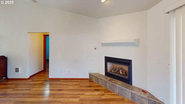 unfurnished living room with hardwood / wood-style floors and a tile fireplace