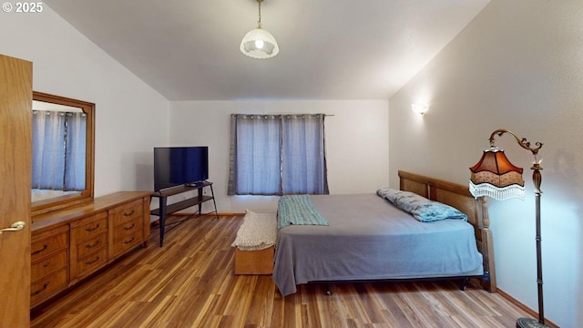 bedroom with lofted ceiling and wood-type flooring