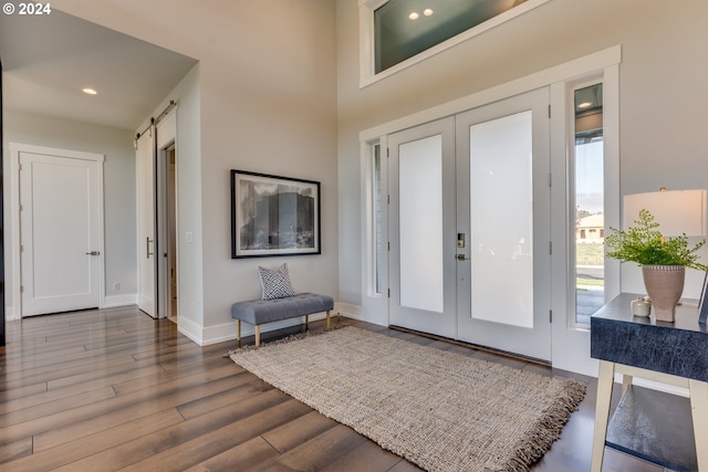 entrance foyer featuring a barn door, french doors, and dark wood-type flooring