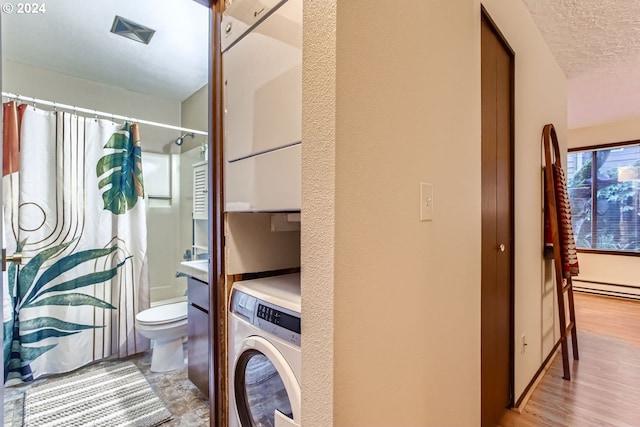 interior space with a baseboard heating unit, light wood-type flooring, a textured ceiling, and washer / dryer