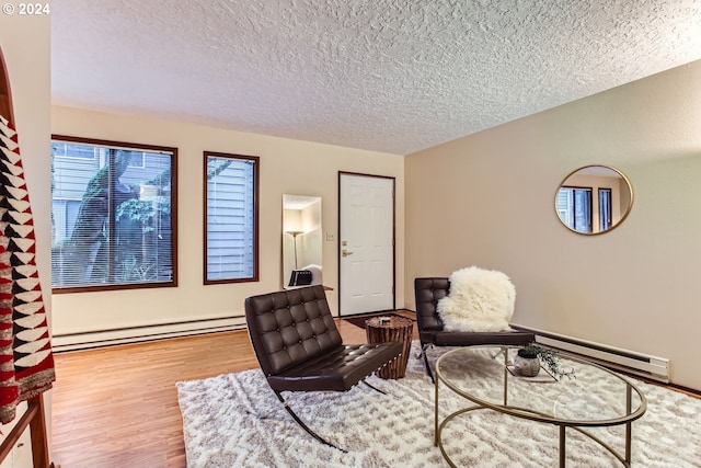 office space with light wood-type flooring, a textured ceiling, and a baseboard heating unit