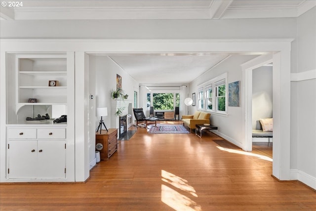 living room with light hardwood / wood-style flooring, built in features, and crown molding