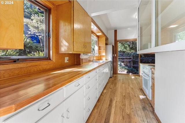 kitchen featuring sink, white oven, light hardwood / wood-style flooring, white cabinets, and range