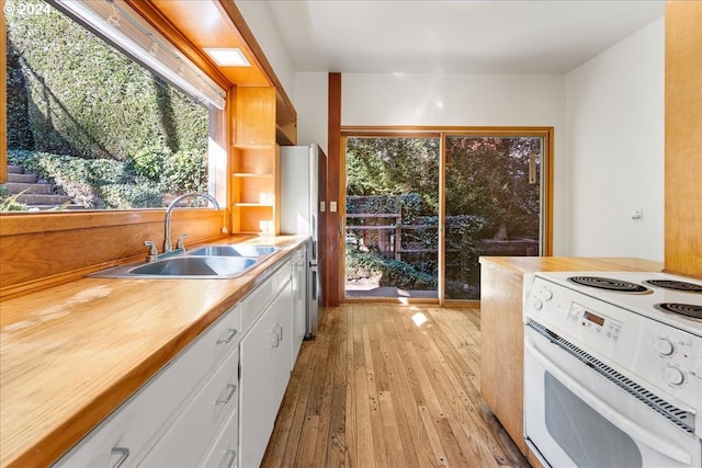 kitchen with white appliances, white cabinetry, sink, and light wood-type flooring