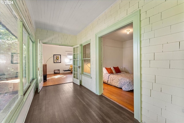 corridor featuring plenty of natural light, dark wood-type flooring, and brick wall