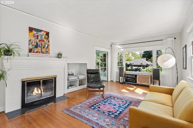 living room with hardwood / wood-style flooring and a brick fireplace