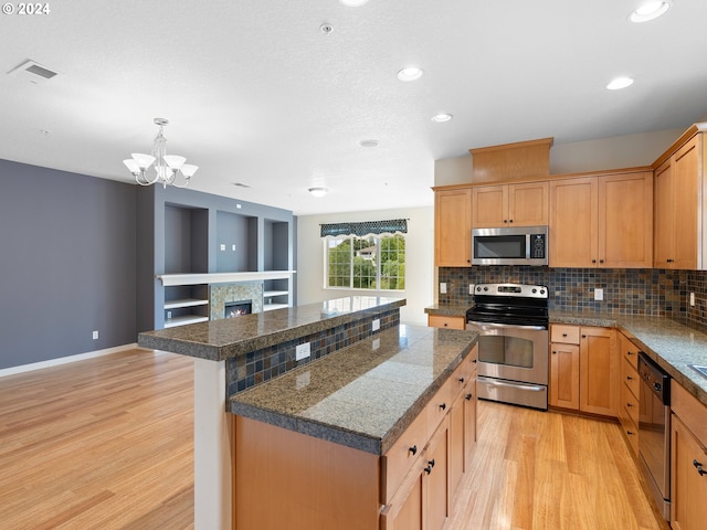 kitchen with stainless steel appliances, a chandelier, a kitchen island, backsplash, and light wood-type flooring