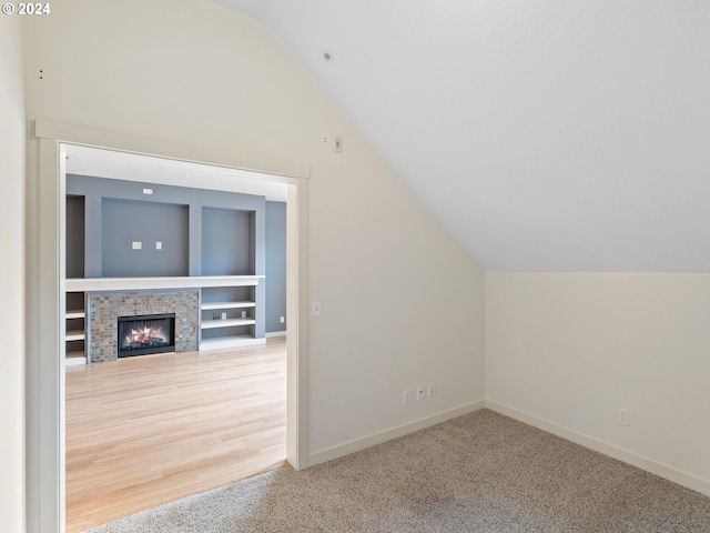 additional living space featuring lofted ceiling, hardwood / wood-style floors, and a fireplace