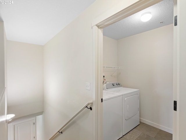 clothes washing area featuring washing machine and dryer, a textured ceiling, and light tile patterned floors