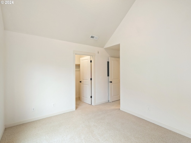 spare room featuring lofted ceiling and light carpet