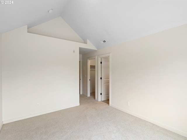 unfurnished room with light colored carpet and lofted ceiling