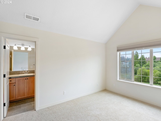 unfurnished bedroom with ensuite bath, light carpet, and vaulted ceiling