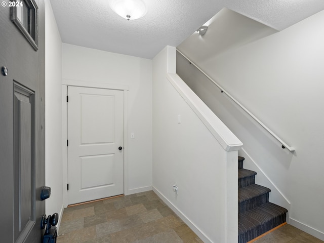 staircase featuring a textured ceiling