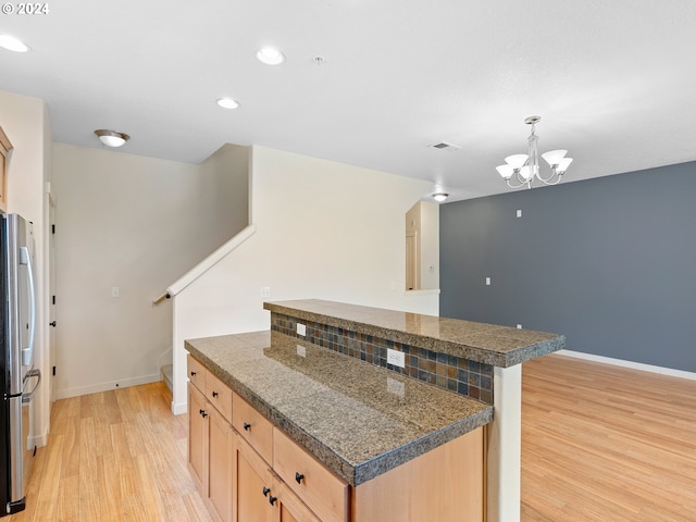 kitchen with light brown cabinetry, a chandelier, stainless steel fridge, and light hardwood / wood-style flooring