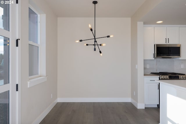 kitchen with hardwood / wood-style flooring, white cabinetry, appliances with stainless steel finishes, hanging light fixtures, and a notable chandelier