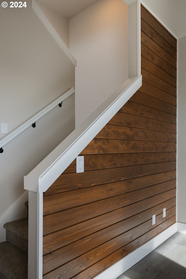 staircase featuring wood walls and hardwood / wood-style floors