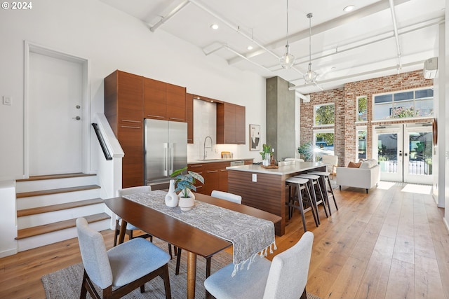 dining room featuring sink, light hardwood / wood-style flooring, french doors, and brick wall