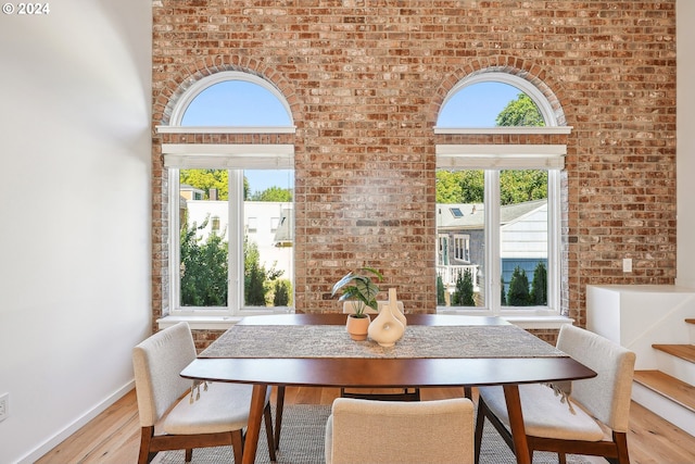 dining space with light hardwood / wood-style flooring and brick wall