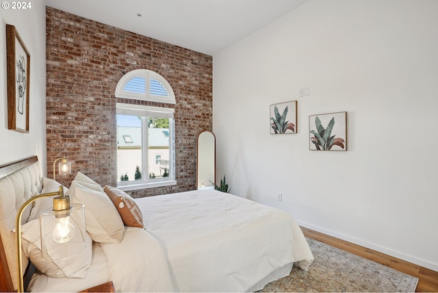 bedroom with brick wall and hardwood / wood-style flooring