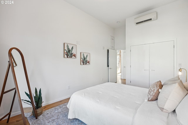 bedroom featuring wood-type flooring, a wall unit AC, and a closet