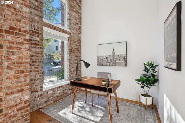 office space with brick wall, plenty of natural light, and hardwood / wood-style floors