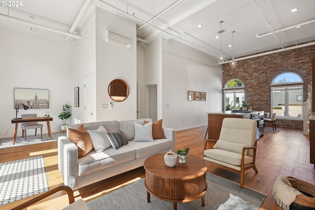 living room with wood-type flooring, a high ceiling, and brick wall