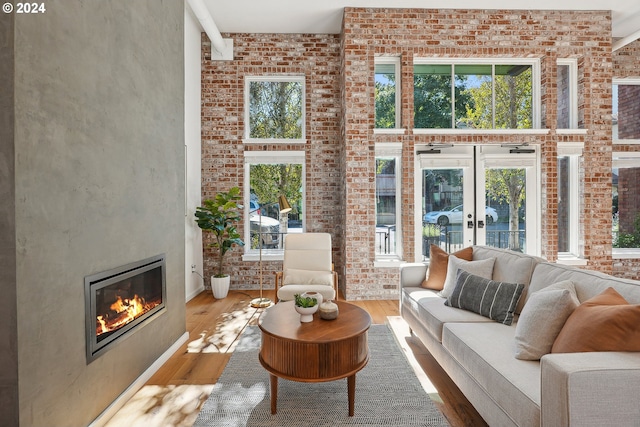 living room with wood-type flooring, a towering ceiling, and brick wall