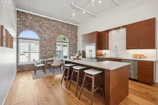 kitchen with a towering ceiling, a center island, stainless steel appliances, and sink