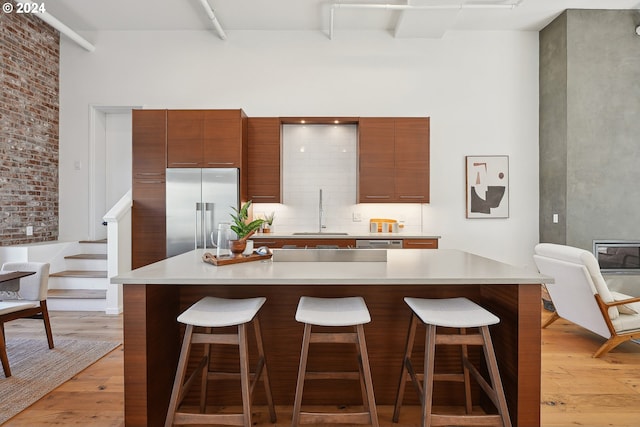 kitchen with a kitchen bar, appliances with stainless steel finishes, sink, and light hardwood / wood-style flooring