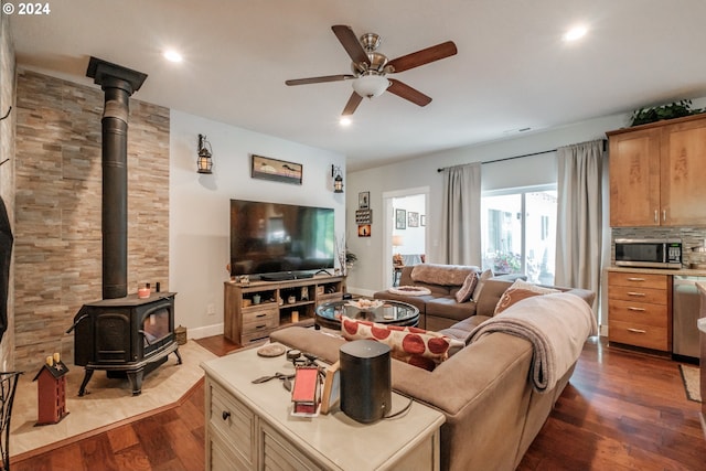 living room featuring ceiling fan, a wood stove, and dark hardwood / wood-style flooring