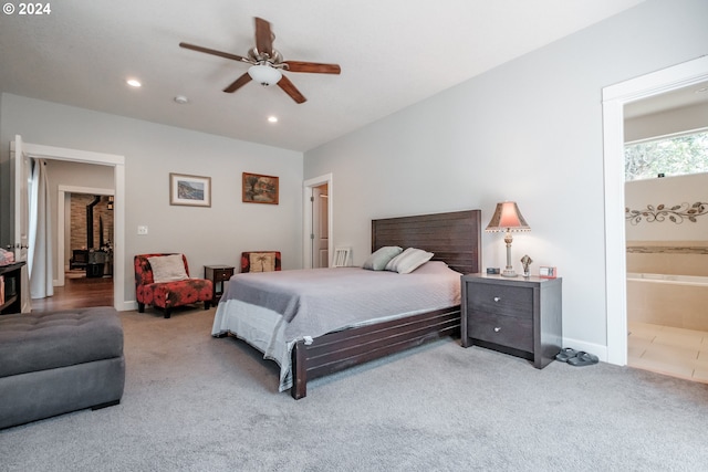 bedroom featuring light colored carpet, ensuite bath, and ceiling fan