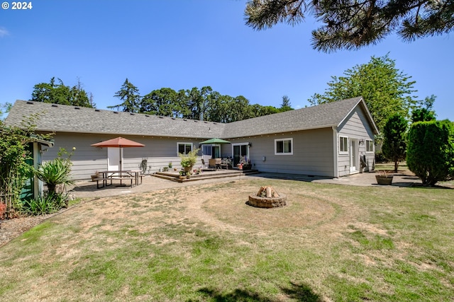 rear view of property with a yard, a patio, and an outdoor fire pit