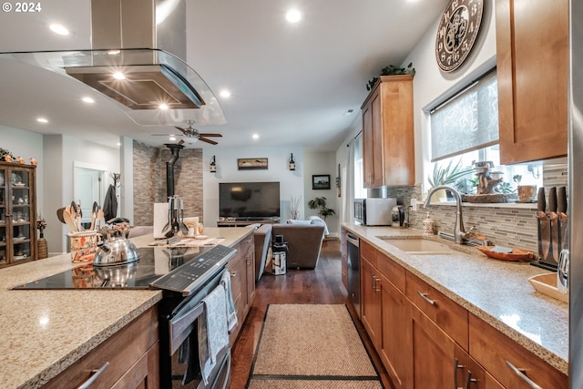 kitchen with light stone counters, stainless steel appliances, sink, dark wood-type flooring, and ceiling fan