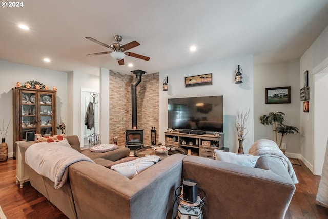 living room featuring ceiling fan, a wood stove, and dark hardwood / wood-style flooring